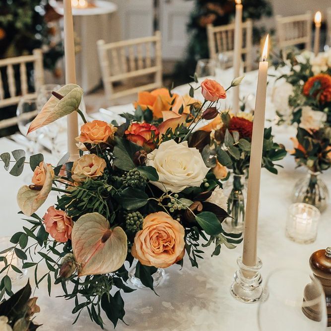 Orange wedding flowers and taper candles table decor