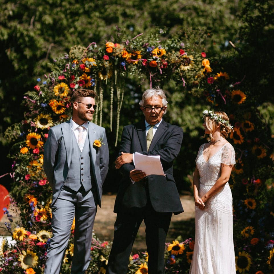Outdoor Wedding Ceremony with Floral Moon Gate, Bride in Jenny Packham Portia Wedding Dress and Groom in Grey Ted Baker Suit