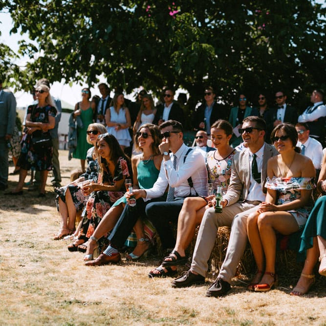 Wedding Guests Sitting on Hay Bales at Outdoor Wedding Ceremony