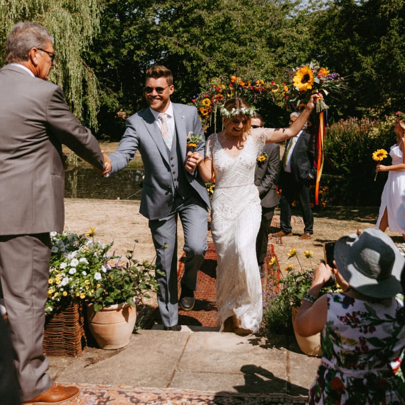 Bride in Jenny Packham Portia Wedding Dress and Groom in Grey Ted Baker Suit Walking up the Aisle as husband &amp; Wife