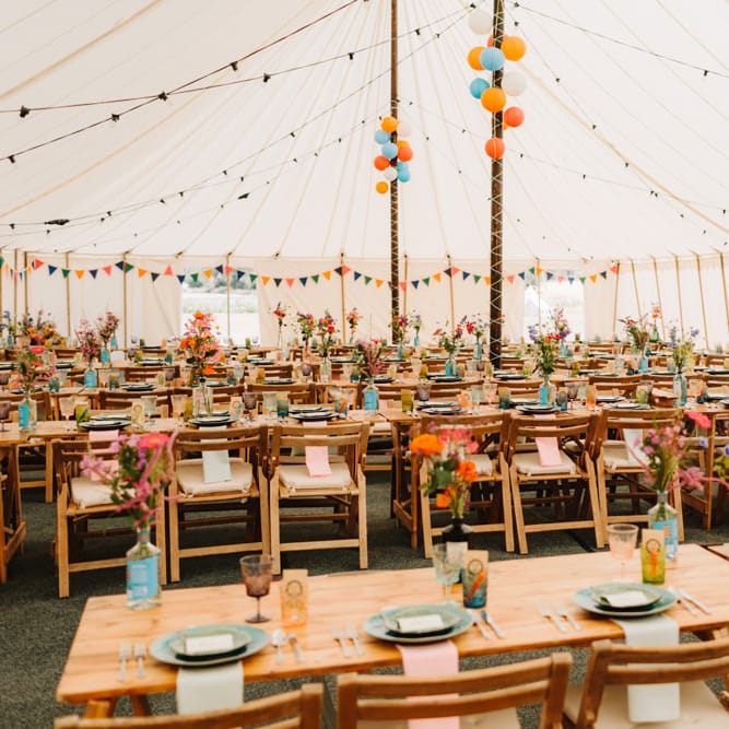 Colourful Marquee Wedding Reception Decor with Wooden Tables and Wild Flowers