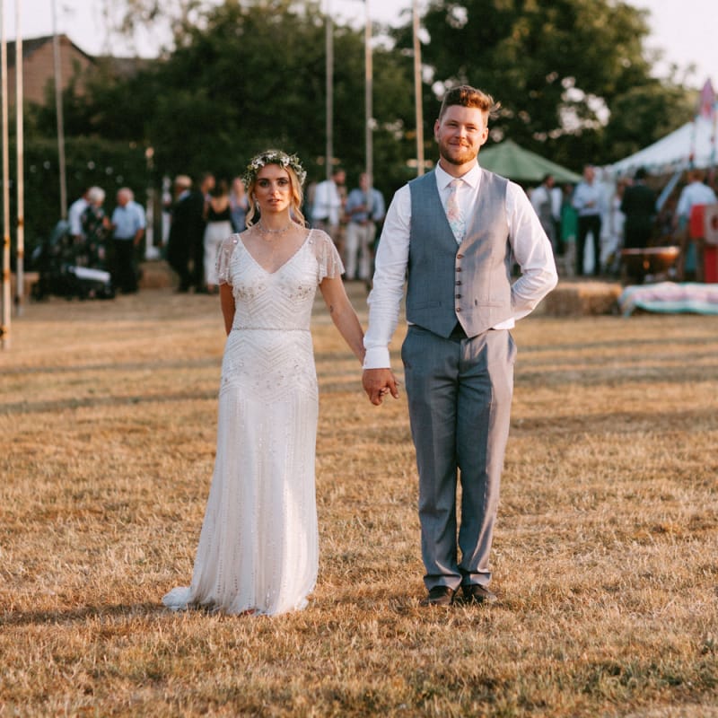 Boho Bride in Jenny Packham Portia Wedding Dress and Flower Crown and Groom in Grey Ted Baker Suit  Holding Hands