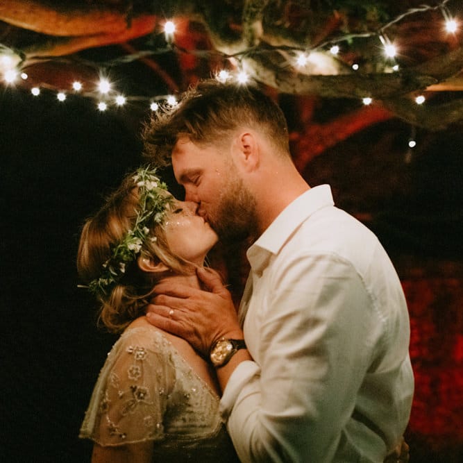 Bride in Jenny Packham Portia Wedding Dress and Flower Crown and Groom in Grey Ted Baker Suit Kissing
