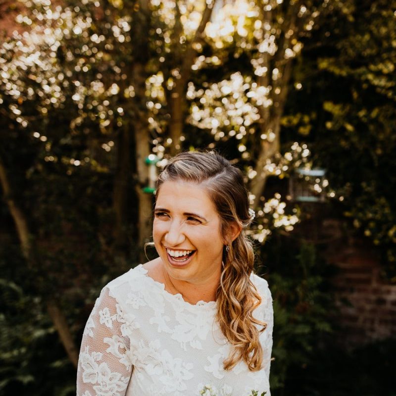 Bridal hair wore in a soft curl to the side teamed with laced long sleeve dress
