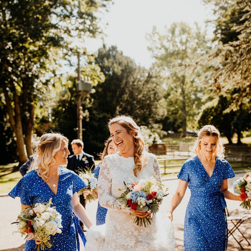 Bride wearing long sleeved laced dress and gold ballet pumps with her bridesmaids wearing blue star print dresses