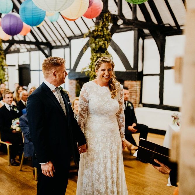 Bride and groom tie the knot at village hall ceremony with colourful hanging lanterns