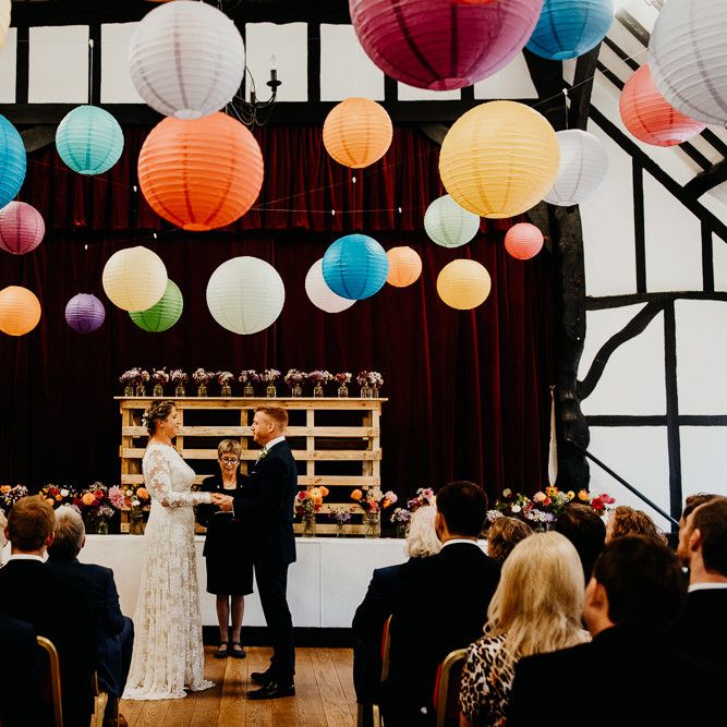 Bride and groom tie the knot at village hall ceremony with colourful hanging lanterns