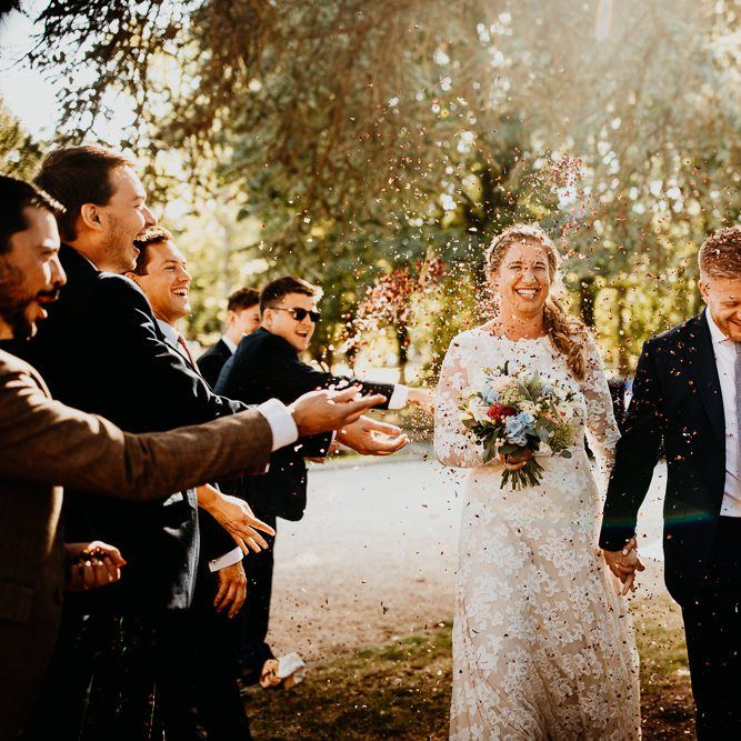 Confetti shot at village hall wedding with bride wearing long sleeved laced dress