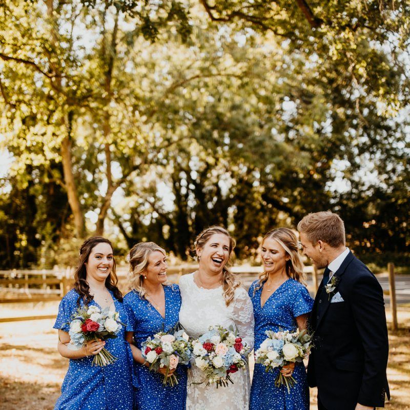 Bridesmaids wearing blue star print dresses with silver shoes and colourful floral bouquets