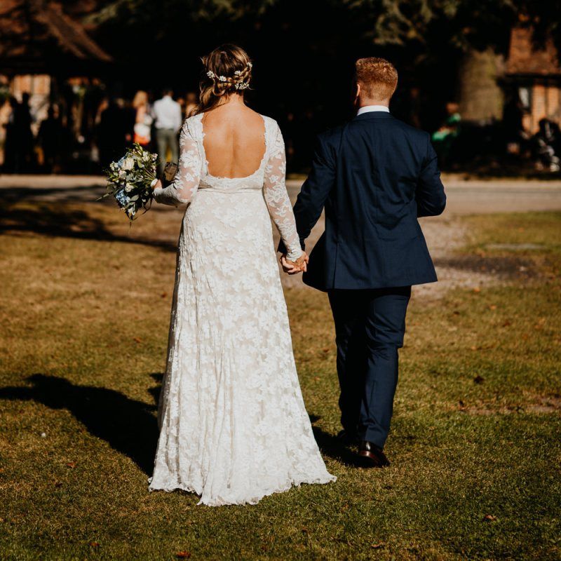 Back of brides beautiful laced dress with delicate hair accessory and soft curls worn to the side