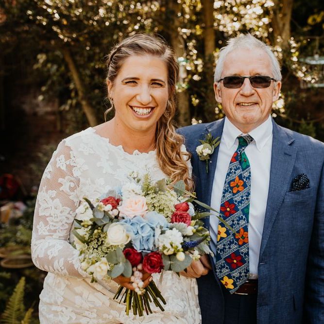 Bride wearing a laced long sleeve dress teamed with bright floral bouquet