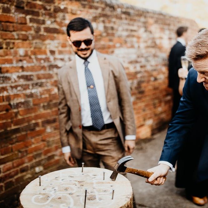 Groom at outdoor drinks reception playing Hammerschlagen