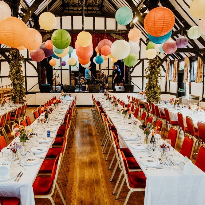 Hanging lanterns and colourful floral arrangements at village hall wedding reception