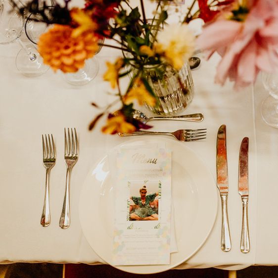 Personalised polaroid image place settings at village hall wedding with bright and colourful styling and hanging lanterns