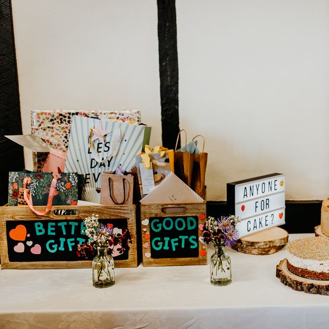 Gift boxes and wedding cakes at village hall wedding with colourful styling and hanging lanterns