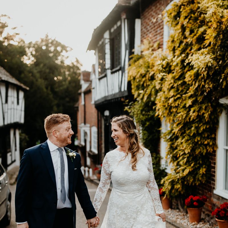 Bride wearing laced long sleeve dress and groom wearing navy two piece suit