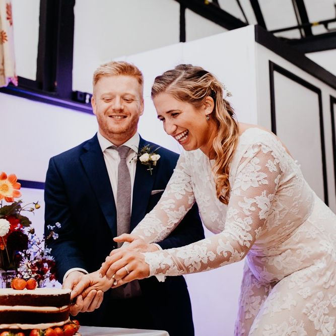 Bride and groom cut the cake decorated with berries and colourful florals