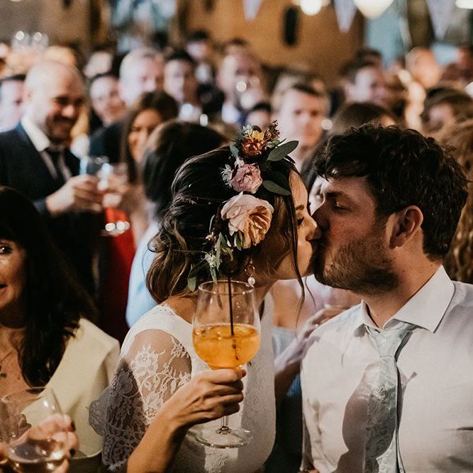 Bride and groom kiss amongst wedding guests at pub party