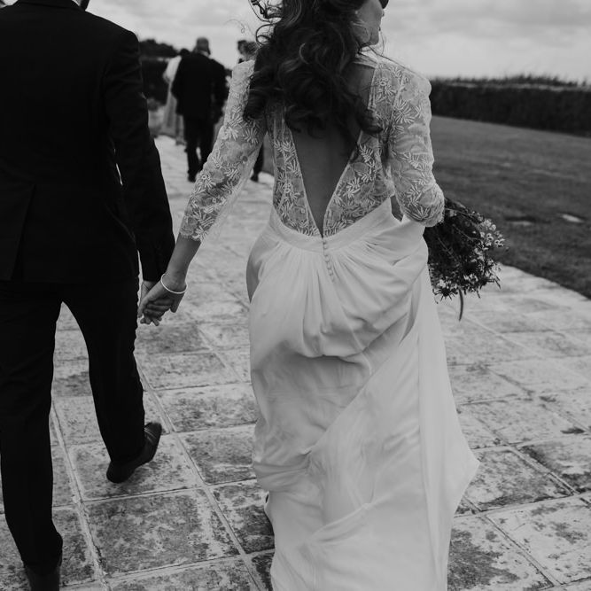 Bride in Donatelle Godart Wedding Dress with Lace V Back &amp; Groom in De Fursac Suit Holding Hands