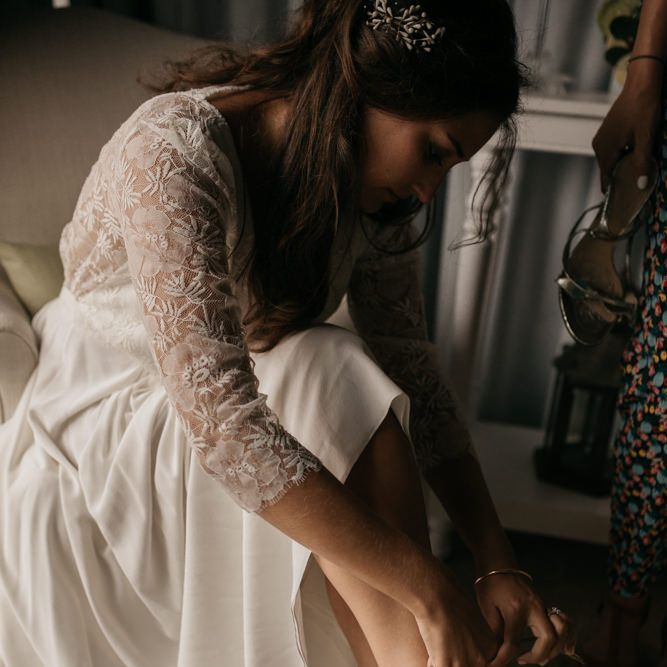 Bride in Donatelle Godart Wedding Dress Putting on Chloé Bridal Shoes