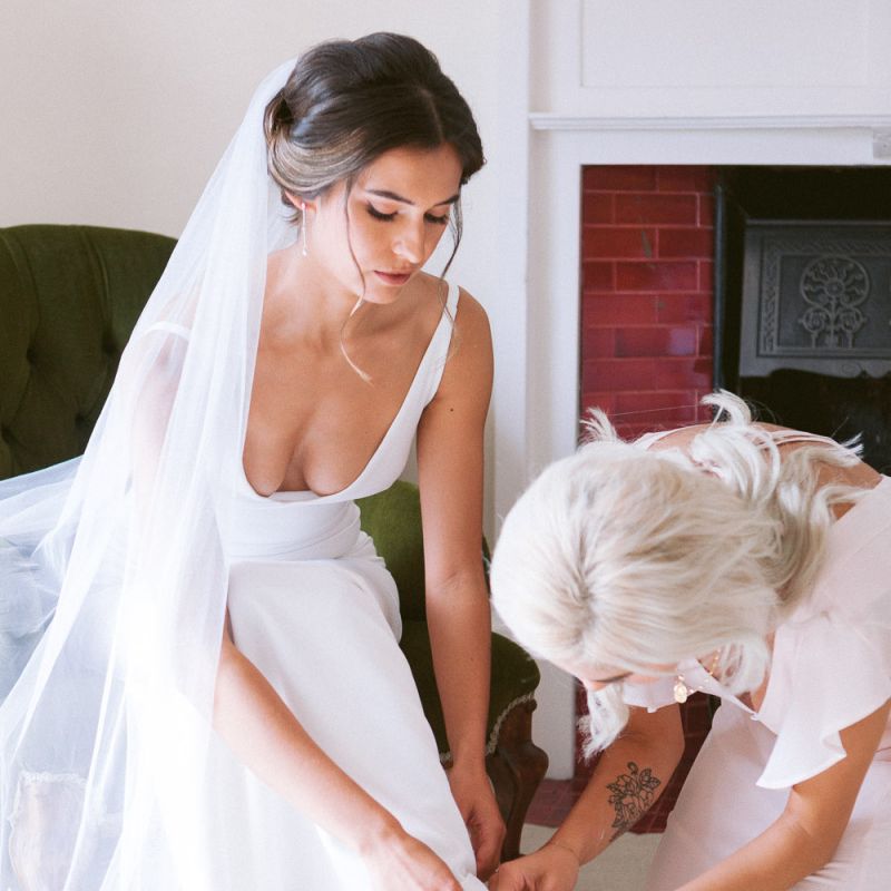 Bride in simple dress puts on nude wedding shoes