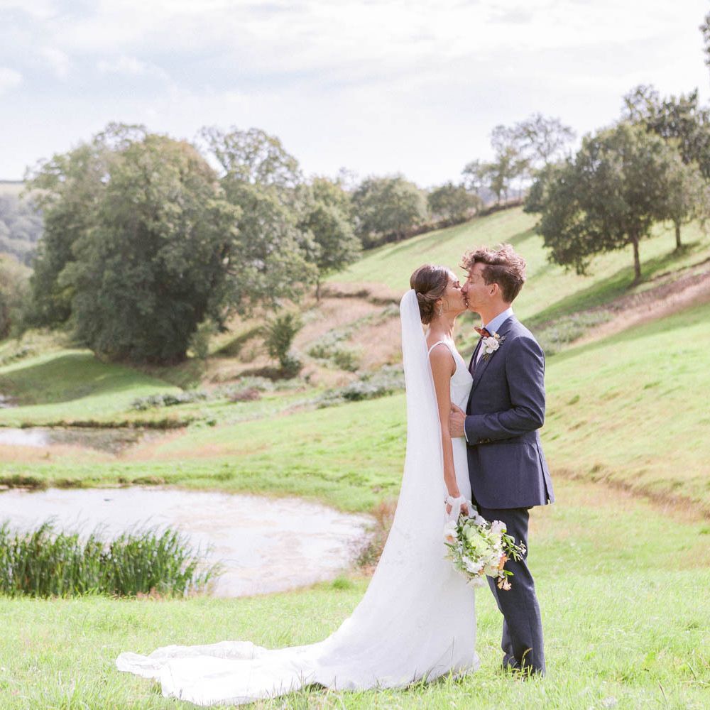 Cathedral veil with lace detail for bride with groom in navy suit and bowtie