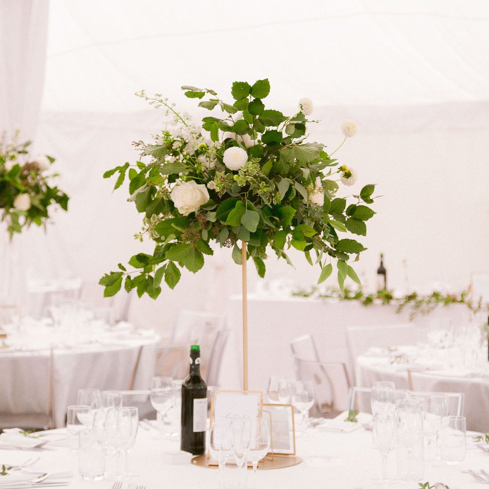 Tall wedding table centrepieces with gold detail and flowers and foliage