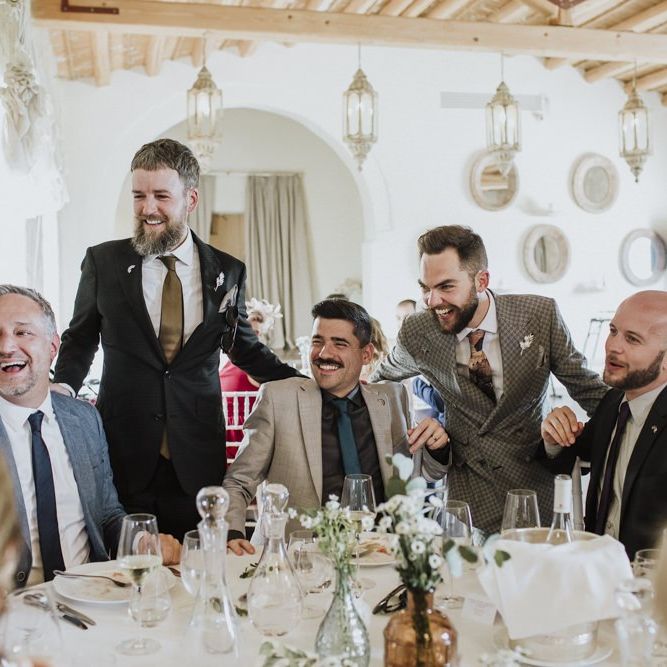 Grooms speak to guests during wedding breakfast in grey groom suit