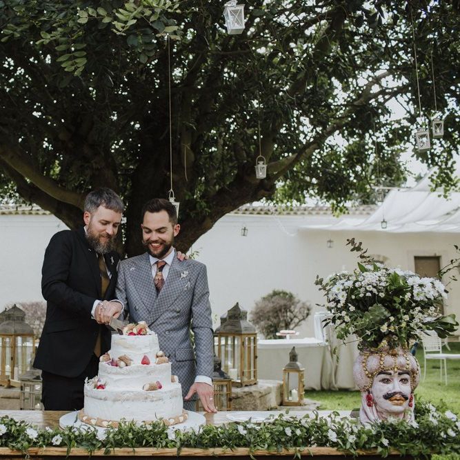 Groom and groom cut the wedding cake in grey groom suit