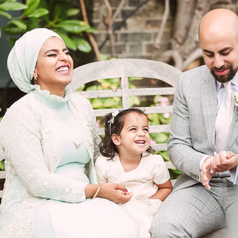 Flower Girl and Her Parents Laughing on a Bench