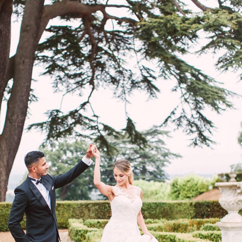 Groom in Black Tie Suit Twirling his Bride in her Lace Pronovias Wedding Dress