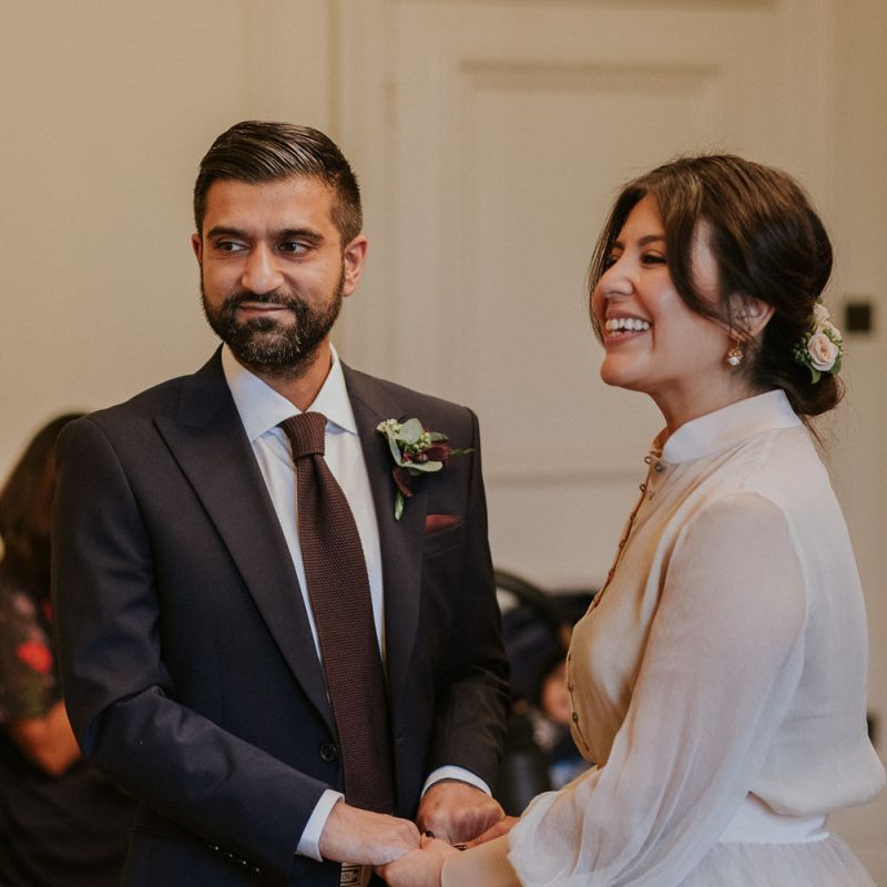 Bride and groom holding hands during town hall wedding reception