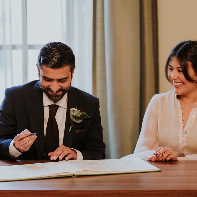 Bride and groom signing the register at intimate town hall wedding