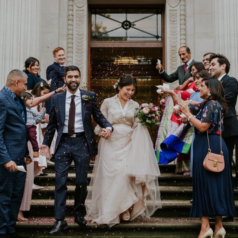 Bride in tulle skirt separates and groom in navy suit at town hall wedding