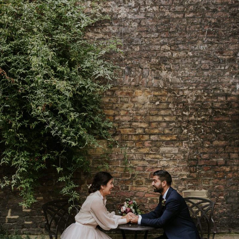 Bride and groom portrait sitting at a table with bride in tulle skirt
