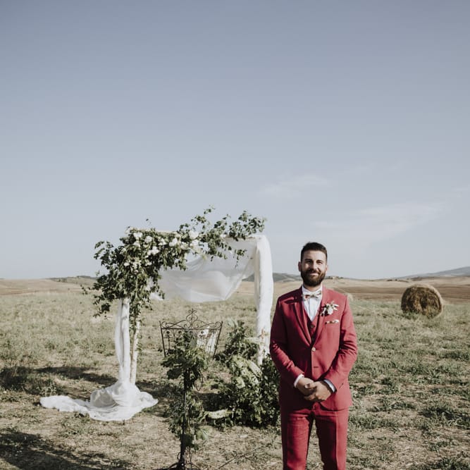 Groom in red suit waits at altar for bride