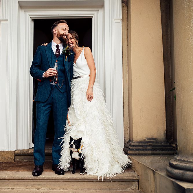 Bride in Charlie Brear Payton Bridal Gown &amp; Piora Feather Skirt and Groom in Three piece Wool Suit with Their Pet Pug