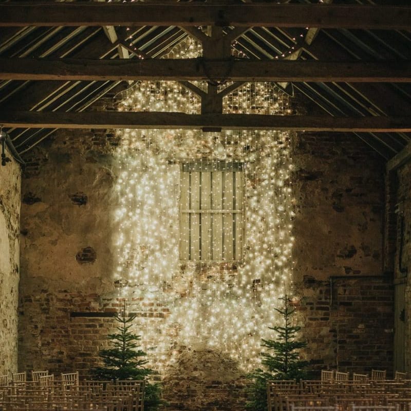 Fairy light curtain for New Years eve ceremony in a barn with Christmas trees and lantern aisle decor