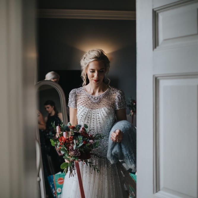 Bride wearing a beautiful embellished wedding dress with festive floral bouquet and a classic red lip