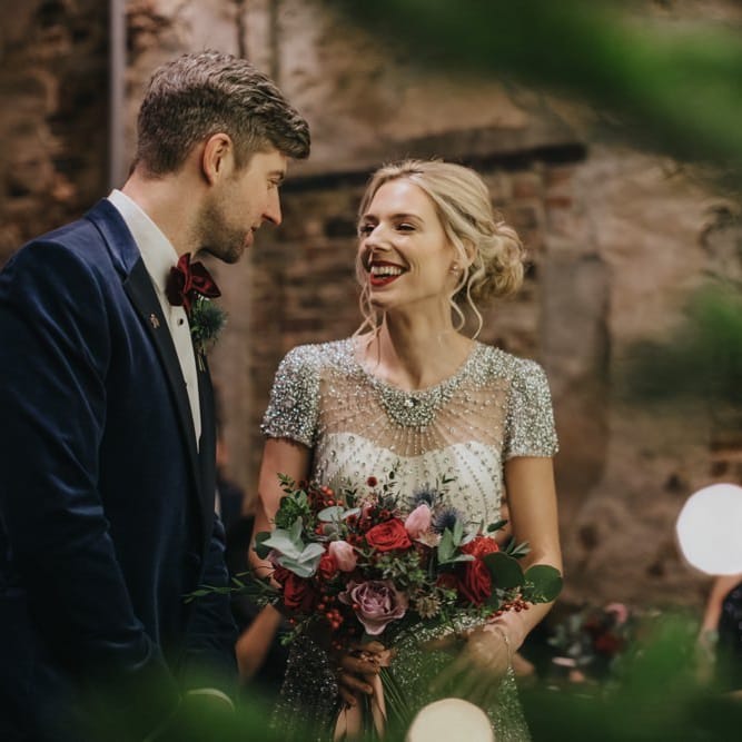 Bride and groom tie the knot at winter ceremony wearing a embellished wedding dress and navy velvet suit