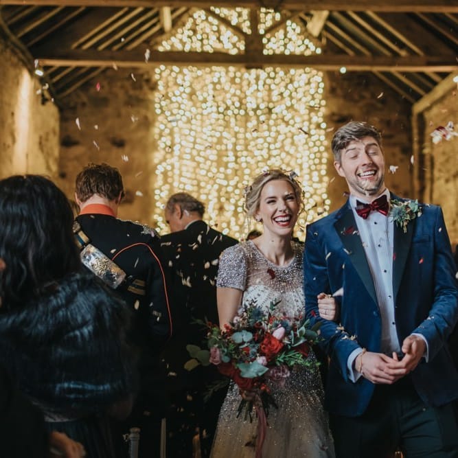 Confetti shot at winter wedding in a barn with fairy light curtain and embellished wedding dress