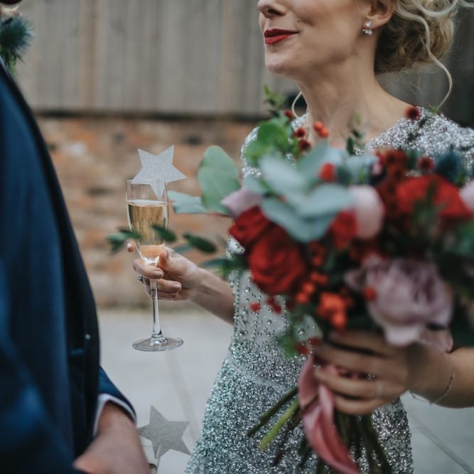 Bride and groom at winter styled wedding with red floral bouquet and a navy velvet suit