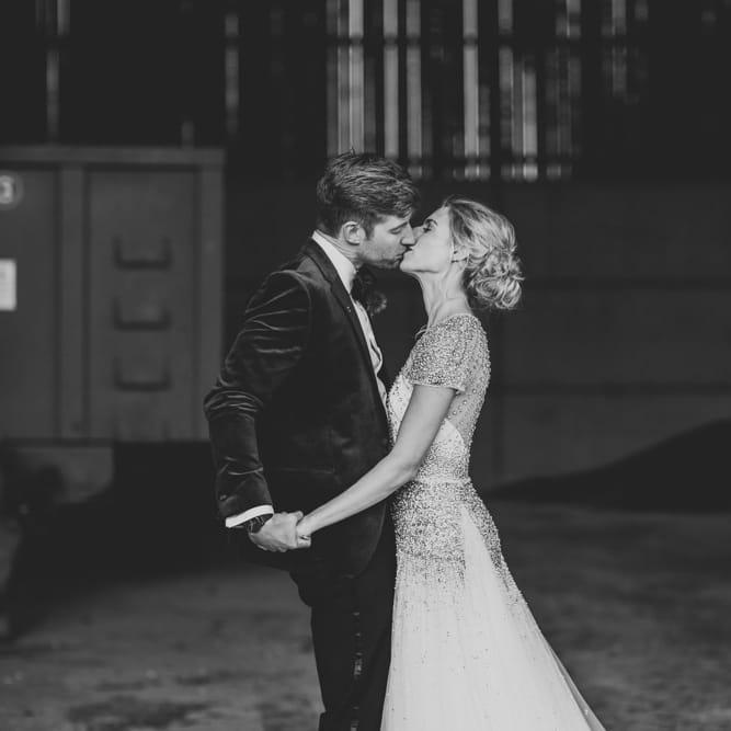 Bride and groom embrace at winter wedding wearing an embellished wedding dress and navy velvet suit
