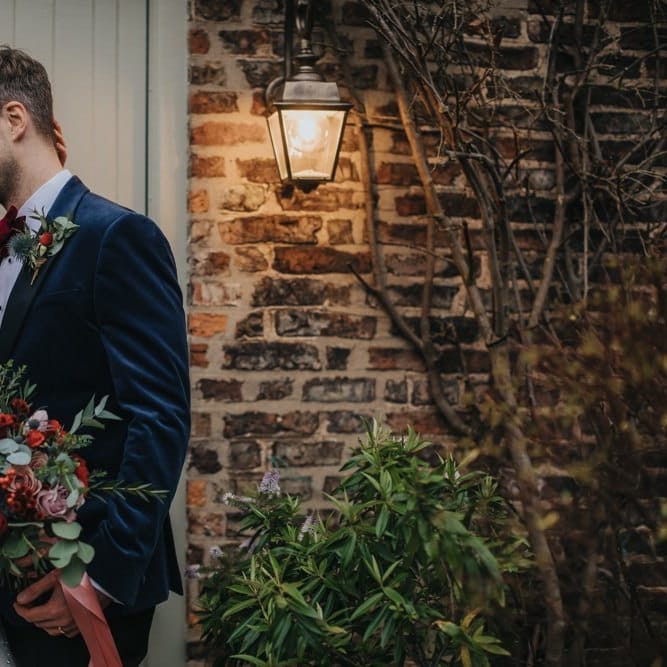 Bride and groom embrace at winter wedding wearing an embellished wedding dress and blue bridal jacket
