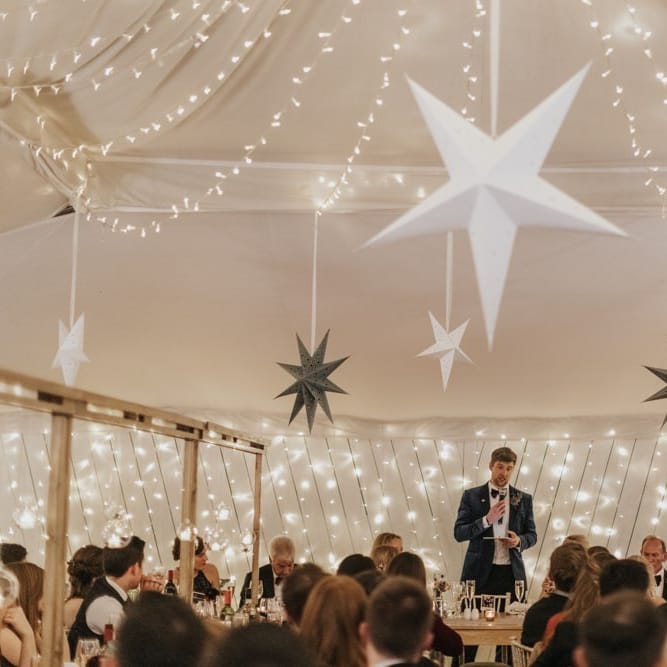 Grooms speech at marquee winter reception styling with star decor and fairy lights for New Years eve celebration