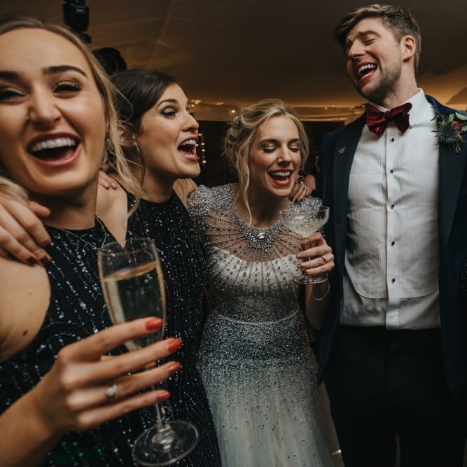 Bride wearing embellished wedding dress and bridesmaids in black dress with black tie winter wedding