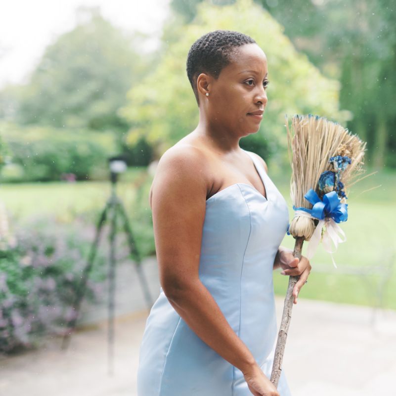 Bridesmaid in strapless blue dress holding a broom