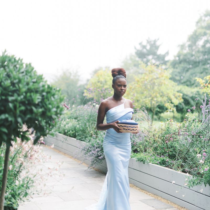 Bridesmaid in blue one shoulder dress holding a gift