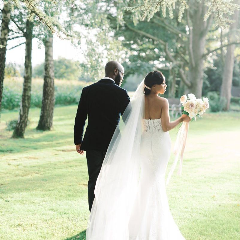 Bride in strapless wedding dress and cathedral length veil and groom in black tuxedo