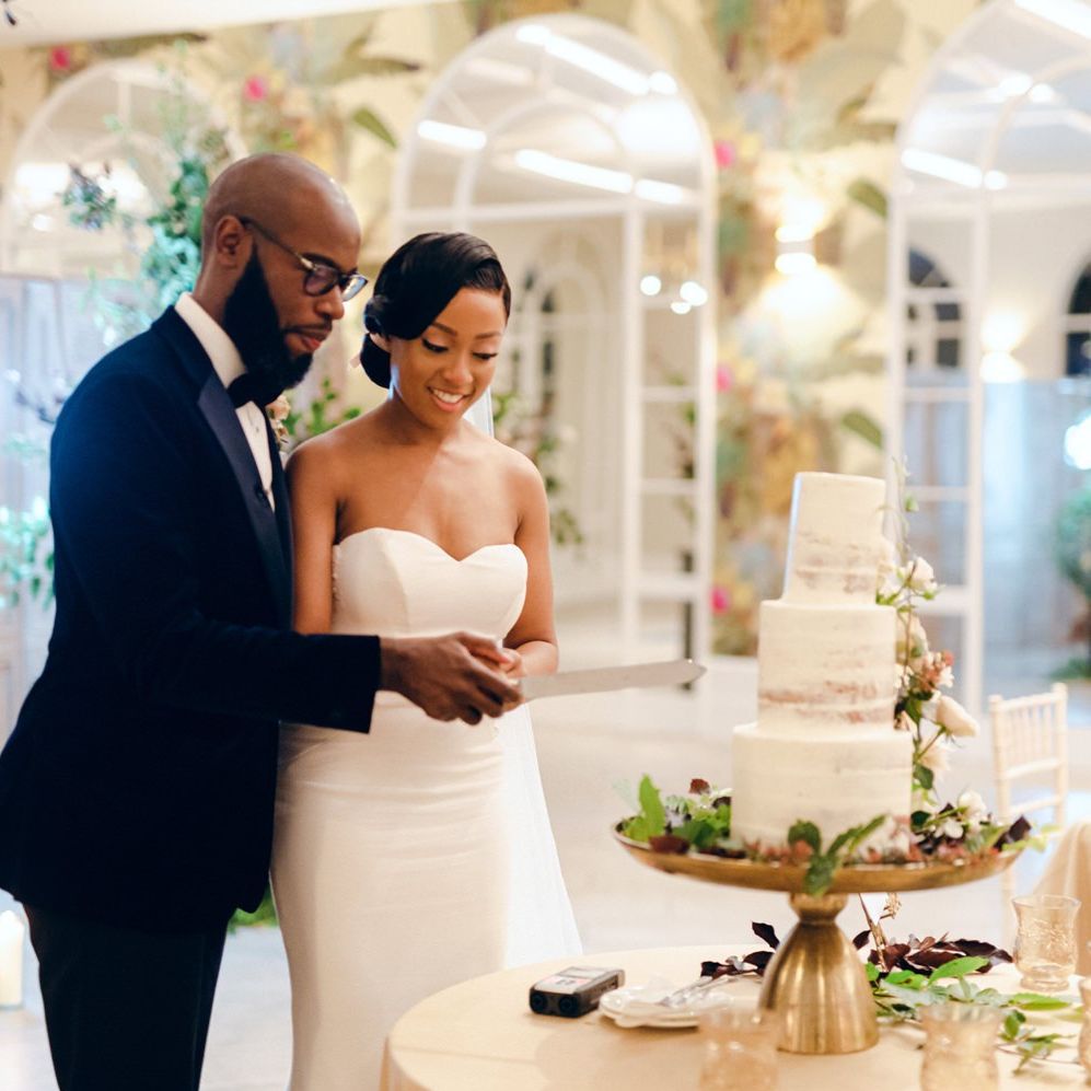 Bride and groom cutting the semi naked wedding cake decorated with flowers